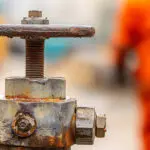 Close-up of a corroded industrial valve showing rust and coating failure, illustrating the signs industrial machinery needs repainting.
